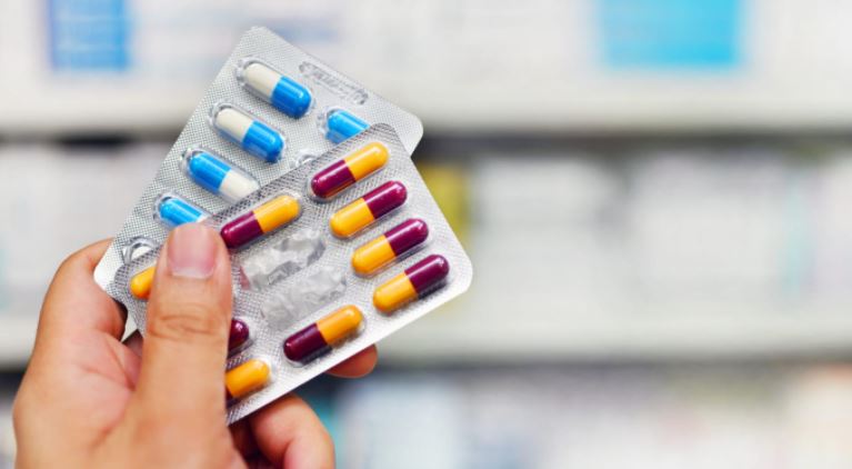 mujer con antibióticos en la mano